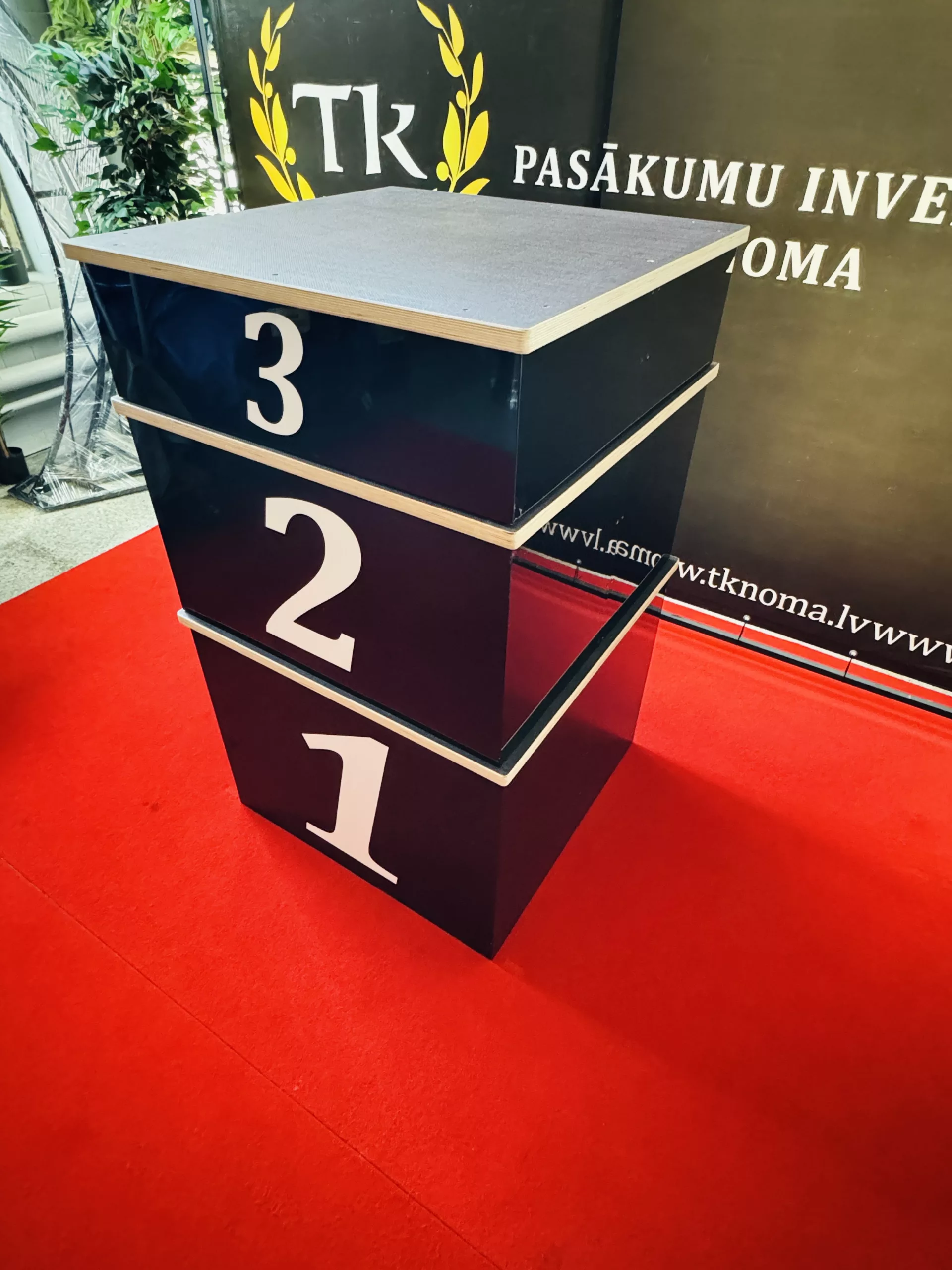 6B2A1CE8-32A9-4864-A7A9-77E69A72B81B Melns apbalvošanas podests (pjedestāls) ar trim pakāpieniem, godalgoto vietu laureātiem